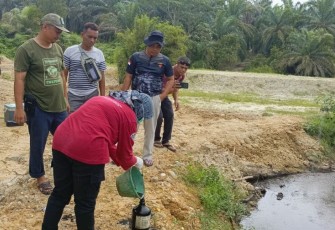 Pihak Polres dan DLH Aceh Singkil saat melakukan penyelidikan dan mengambil sampel air sungai yang tercemar.