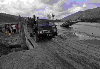 Sejumlah kendaraan melewati jembatan darurat yang dibangun untuk kembali menghubungkan akses jalur provinsi Aceh Timur-Gayo Lues, di kilometer 83 Peureulak-Lokop pascabanjir bandang di Gampong Lokop, Kecamatan Serbajadi, Kabupaten Aceh Timur, Provinsi Aceh, Sabtu (10/1).