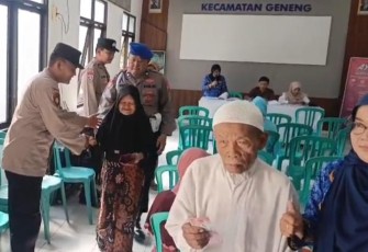 Aksi Humanis Polsek Geneng Bantu Lansia yang Antri Terima PKH Plus di Ngawi