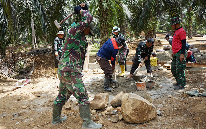 (Batu-batu besar dipecah untuk menambah material pengerasan sebagian jalan yang masih berlumpur. Tim Satas dan masyarakat kompak bergotong-royong dalam sasaran fisik plat duiker)