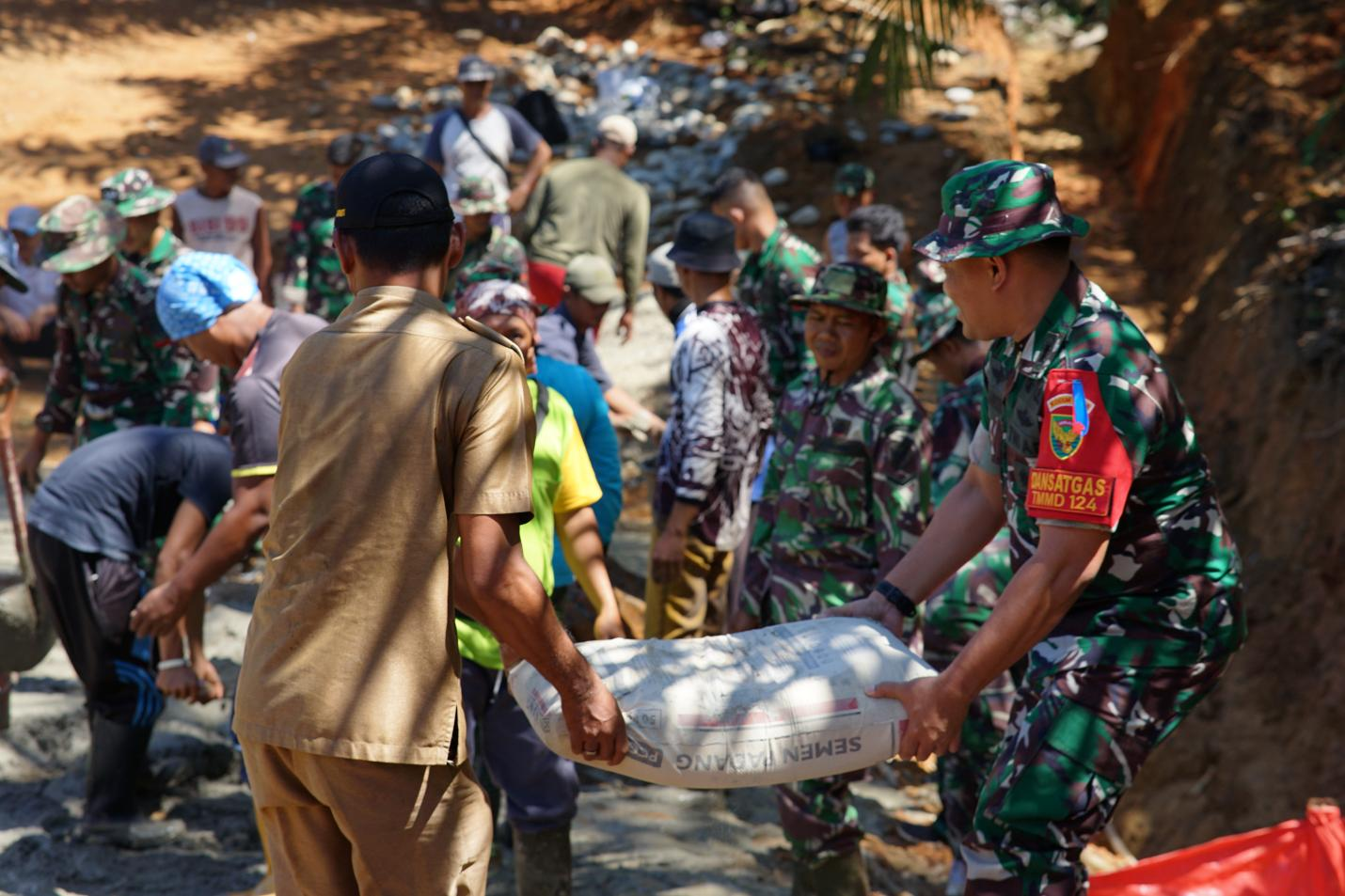 Aku dan Kades Bandu Agung turut membantu satgas dan masyarakat mengangkat semen untuk pengecoran plat duiker.