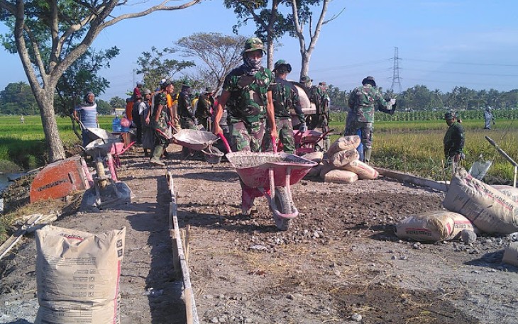 Personil TNI Melangsir Adonan Matrial Dengan Angkong 