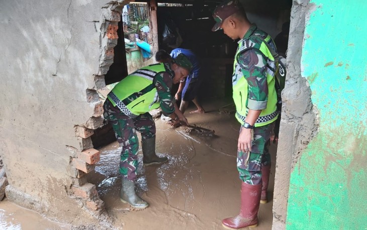 Nampak aparat TNI saat membersihkan lumpur di salah satu rumah warga yang terdampak banjir