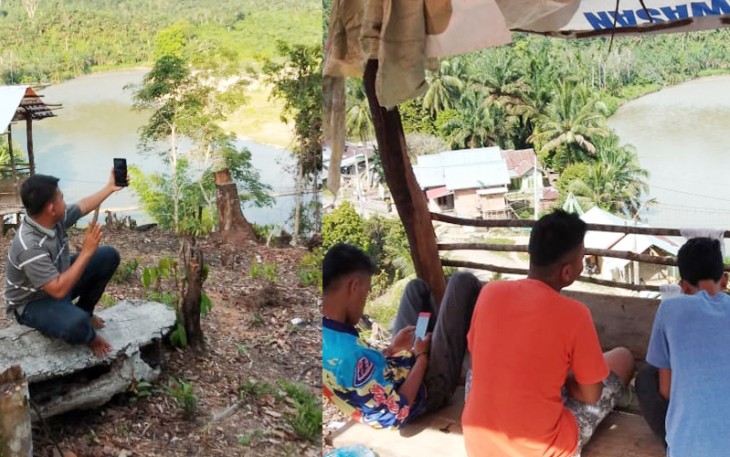 Para pemuda tampak mencari sinyal didekat sungai desa setempat