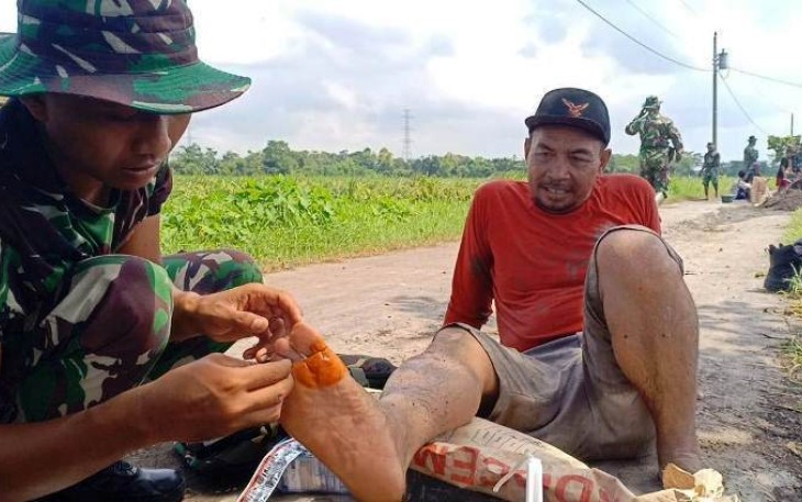Praka Arif Wicaksono anggota Peleton Kesehatan dari Yonif 407 Padma Kusuma sedang memberikan pertolongan pertama kepada Drajat (60)