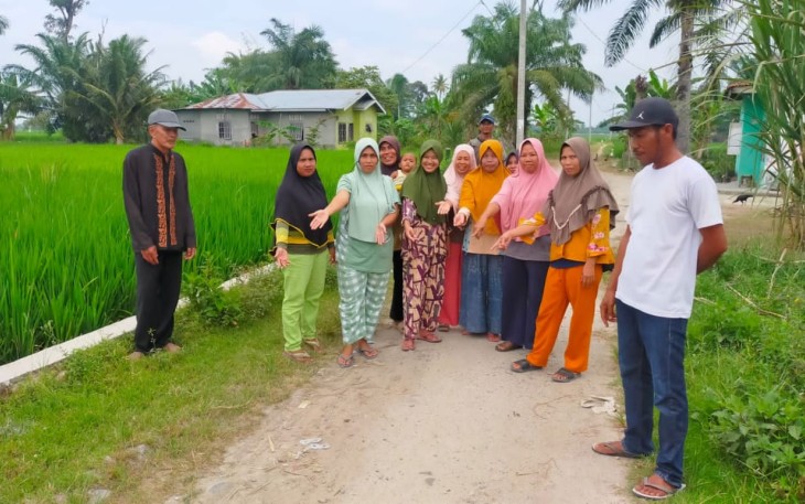 Ibu-ibu, warga setempat memperlihatkan jalan yang rusak dan berharap segera diperbaiki.