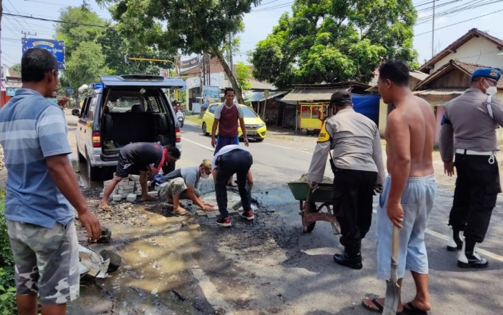 Jajaran Polsek Ngunut Polres Tulungagung melaksanakan kegiatan tanggap keselamatan berlalu lintas dengan melaksanakan penambalan jalan berlubang 