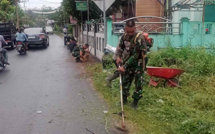 Sertu Gatot Subroto saat memotong rumput di bahu jalan desa. Kamis (29/9)