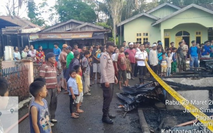 Petugas Polsek Sipirok memasangi garis polisi di lokasi kejadian Kebakaran.
