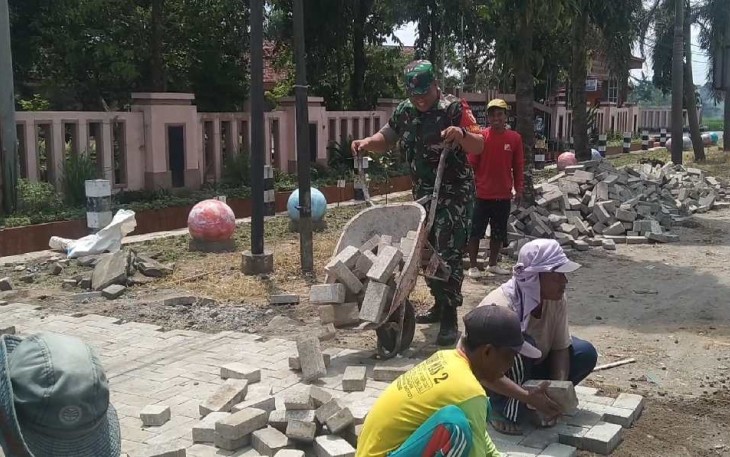 Pemasangan paving blok di halaman balai desa wilayah binaan, Minggu (17/9)
