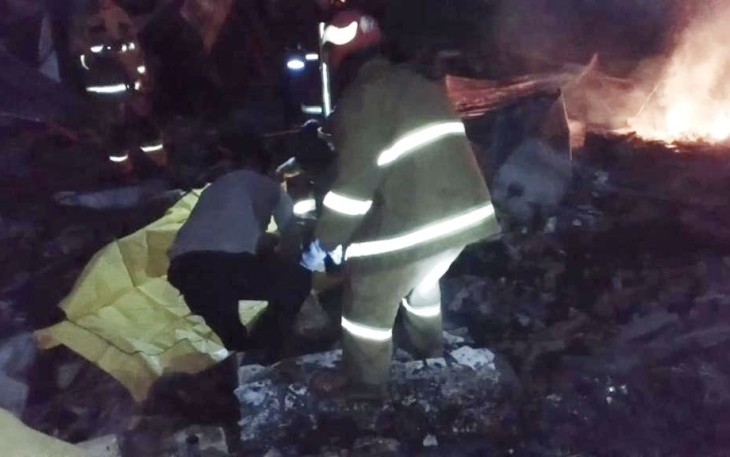 Petugas kepolisian evakuasi korban terbakar di TKP lapak barang bekas terbakar di kampung Tapos desa Cibinong, Minggu (8/1)