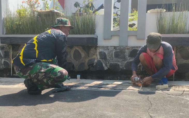 "Anggota Satgas TMMD sedang menganyam besi sloof bersama warga"