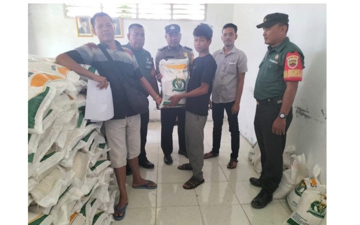 Bhabinkamtibmas Polsek Dolok, Aiptu Monang Siregar, saat mengawal penyaluran bantuan beras
