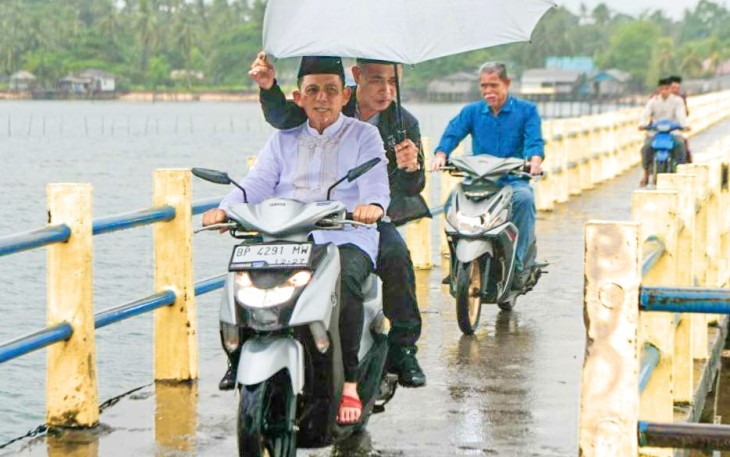 Dengan menggunakan sepeda motor...Ansar tersenyum ke masyrakat pulau Karas 