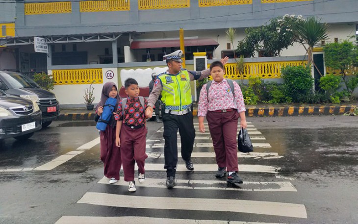 Polisi saat membantu anak-anak menyebrang jalan.
