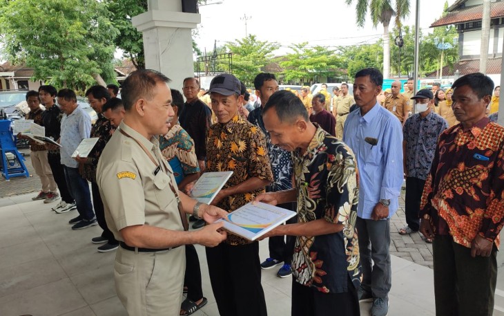 Asisten II Bidang Perekonomian dan Pembangunan Sekda Karanganyar, Titis Sri Jawoto secara simbolis menyerahkan bantuan keuangan dan alsintan kepada perwakilan kelompok tani, di halaman kantor Dispertan PP Karanganyar, Senin (16/12/2024)
