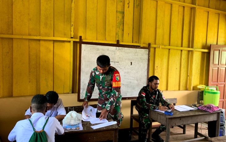 Babinsa Koramil 1710-06/Agimuga Serda Margo Triyanto membantu proses belajar mengajar kepada siswa-siswi SMP Negeri Agimuga di Kampung Kiliarma, Distrik Agimuga, Kab. Mimika, Senin (3/6/2024)