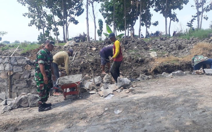 Babinsa Desa Sukisari Laksanakan Karya Bakti Pembuatan Talud Jalan 