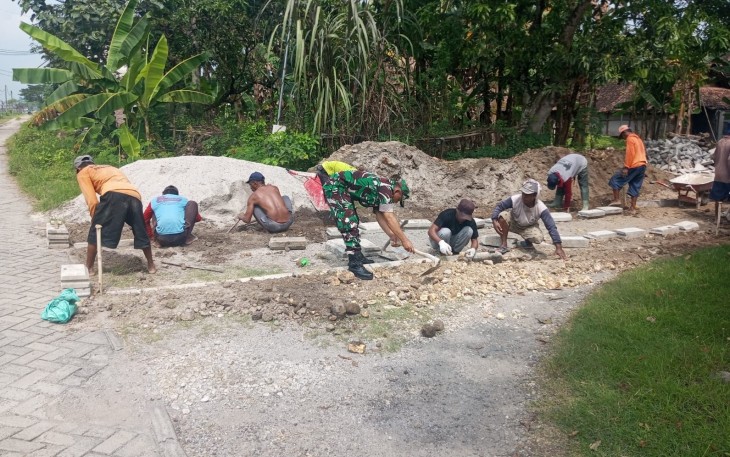 Babinsa Koramil Pilangkenceng Bantu Warga Pasang Paving Jalan di Dusun Panjen