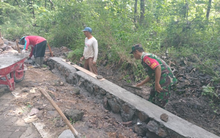 Babinsa Koramil Widodaren  Kodim 0805/Ngawi Serru Joko Priyanto tampak sedang membantu membenahi pembangunan talut dan irigasi bersama masyarakat di Desa Widodaren, Kecamatan Widodaren, Minggu (12/01/2025)