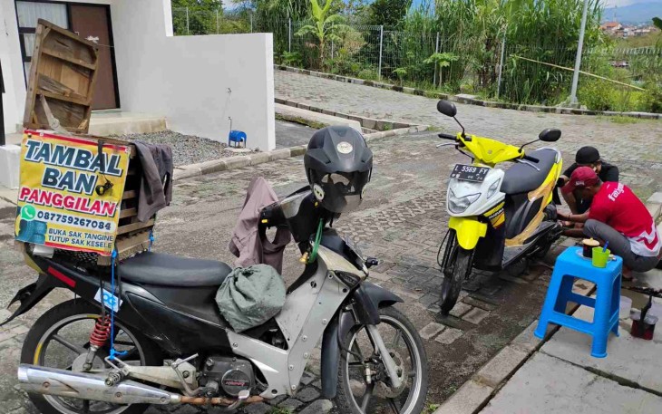 Sugianto, saat tengah melayani pelanggan dengan menambal ban sepeda motor yang bocor. Selasa (11/11)
