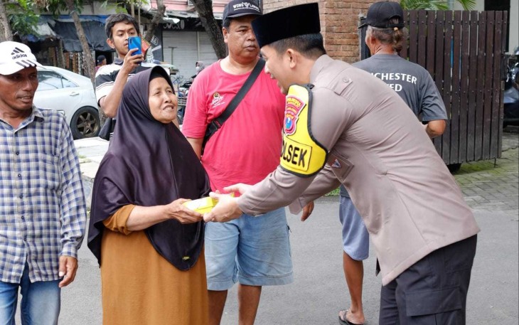 Kapolsek Taman Kompol Kanisius Pranata memberikan makanan dalam kegiatan Jum'at berkah 