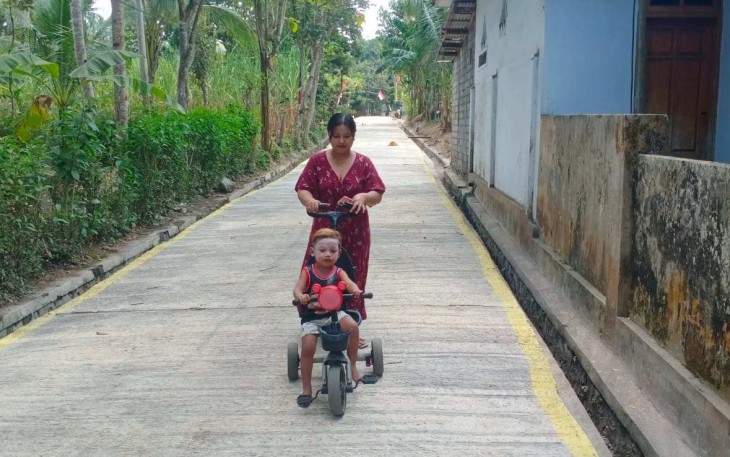Ibu Marisa saat momong anak melintasi jalan rabat beton TMMD