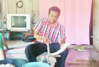 Kades Melati Harjo Dukut Sumari S.IP saat mencoba mengiris singkong dalam produksi keripik singkong milik salah satu warganya