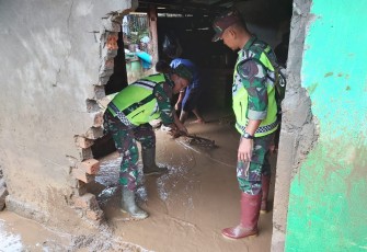 Nampak aparat TNI saat membersihkan lumpur di salah satu rumah warga yang terdampak banjir