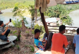 Para pemuda tampak mencari sinyal didekat sungai desa setempat