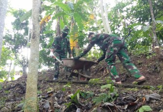 Dua Anggota Satgas TMMD Saling Kerjasama dalam Pengedropan Batu Bahan MCK Umum