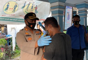 Kapolres Bitung saat memakaikan masker kepada salah satu warga yang terjaring Operasi Yustisi