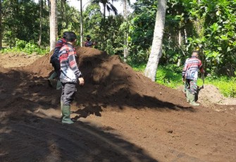 Personil satgas melakukan pembersihan samping bahu jalan