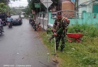 Sertu Gatot Subroto saat memotong rumput di bahu jalan desa. Kamis (29/9)