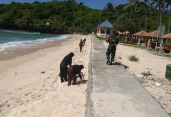 Babinsa Koramil 0801/12 Pringkuku saat Gelar Aksi Sosial Bersihkan Pantai.