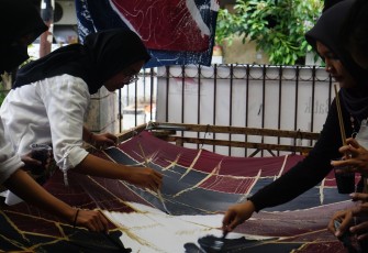 Mahasiswa KKN yang sedang melakukan proses cat pada kain. Foto:Lidia Pratama Febrian
