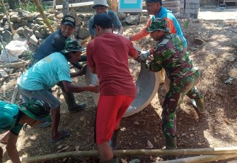 "Satgas TMMD bersama warga sedang menurunkan Bis"