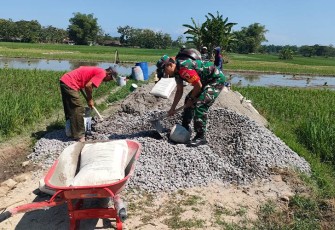 Babinsa Koramil Geger Bantu Warga Bangun Infrastruktur Jalan Sawah.