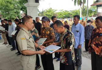 Asisten II Bidang Perekonomian dan Pembangunan Sekda Karanganyar, Titis Sri Jawoto secara simbolis menyerahkan bantuan keuangan dan alsintan kepada perwakilan kelompok tani, di halaman kantor Dispertan PP Karanganyar, Senin (16/12/2024)