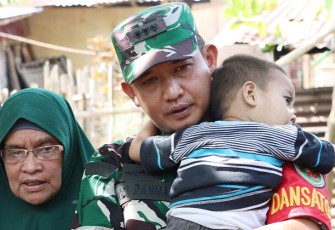 Menunjukan kasih sayang, Dandim 0407/Kota Bengkulu Kolonel Inf Widi Rahman menggendong buah hati pasutri penerima rehab RTLH.