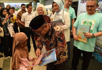 Mendikdasmen Abdul Mu'ti saat memberikan buku bacaan di stasiun Pasar Senen, Jakarta, Rabu (26/3)