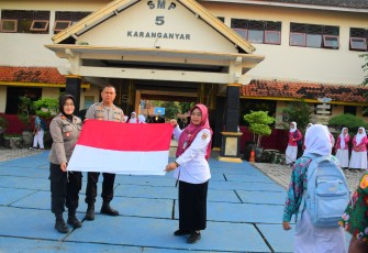 Kapolres Karanganyar, AKBP Hadi Kristanto, didampingi Kapolsek Karanganyar, AKP Nawangsih Retno Waruju, saat membagikan bendera merah putih di SMP 5 Karanganyar, Rabu (6/8/2025) pagi.