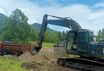 Foto satgas TMMD Kodim 1310/Bitung dengan menggunakan excavator melakukan pemerataan material pengerjaan pengerasan jalan