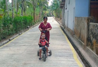 Ibu Marisa saat momong anak melintasi jalan rabat beton TMMD