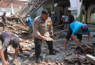 Aiptu Awang membersihkan material Masjid Al Islah yang atapnya ambruk bersama warga, Selasa (18/8)