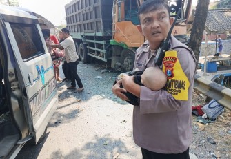 Aipda Sutrisno mengevakuasi bayi korban laka bus di Nganjuk
