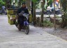 Pak Ramli penjual sayuran melewati jalan rabat beton